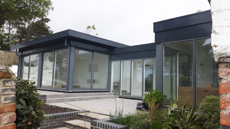 Steel framed extension in Lyme Regis Dorset patio bifold aluminium doors large paved paving area stainless steel handrail salt air flat roof