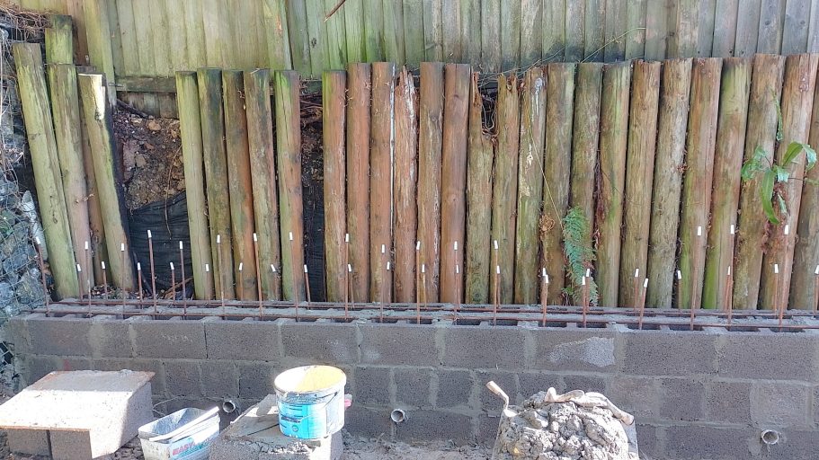 The steel reinforcing bar protrudes out of the top of the concrete blocks to add strength. The steel reinforcing bar protrudes out of the top of the concrete blocks to add strength.